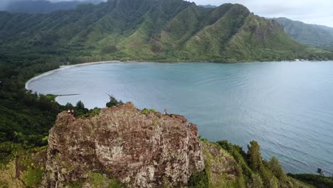 drone shot flying away from a pair of hikers standing on top of the cliffs at the crouching lion hike on oahu, hawaii