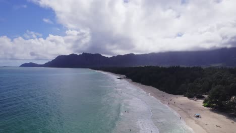 drone-footage-along-the-sandy-shore-of-Oahu-Hawaii-at-Waimanalo-Bay-on-the-left-and-lush-greenery-and-mountains-along-the-shore