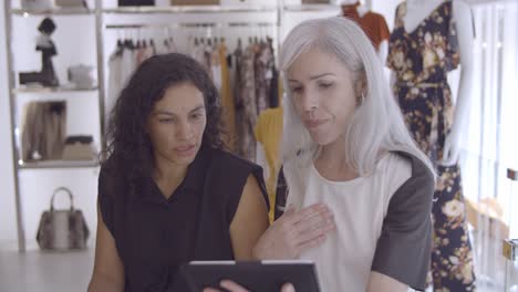 reunión seria de clientes y asistentes de tiendas en una tienda de moda con una tableta