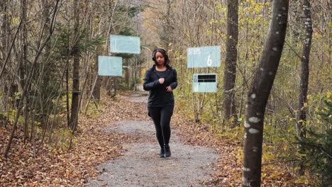 mujer deportiva comienza a correr a través del bosque de otoño - hologramas de seguimiento generados digitalmente para pasos, música y monitoreo del pulso