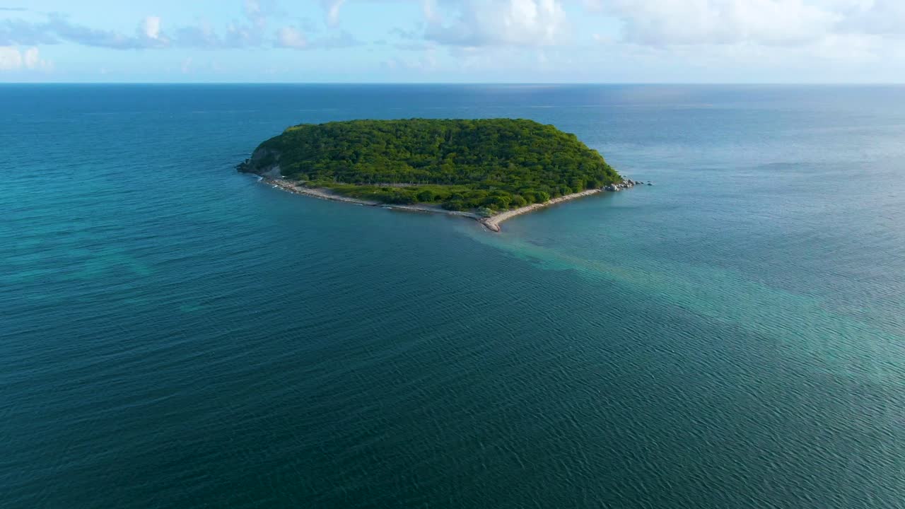 Aerial approaching Isla Real, Puerto Rico with blue sky and fluffy clouds on the horizon