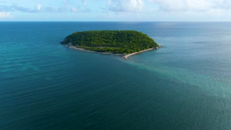 aerial approaching isla real, puerto rico with blue sky and fluffy clouds on the horizon