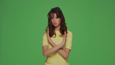 심각한 젊은 소녀는 중단 제스처를 보여주고, 항의, 부인, 경고, 금지 크로마 키 녹색 스튜디오 배경