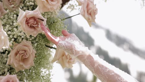 bride's hand reaches for butterfly sitting on wedding flowers and butterfly flies away