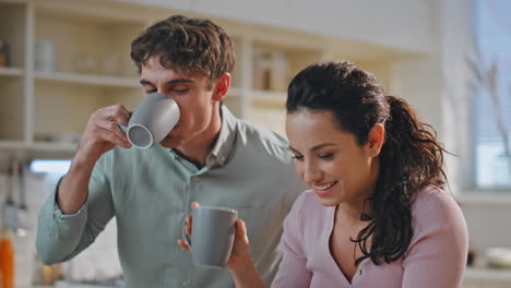 pareja casada bebiendo café riendo hablando juntos en la cocina de casa de cerca