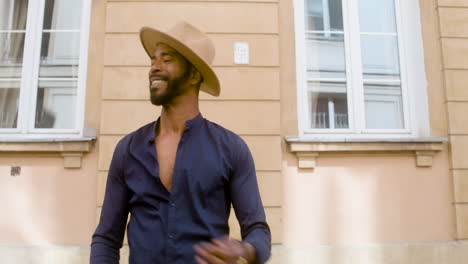 uomo afro caraibico sorridente con cappello panama che balla salsa da solo in strada