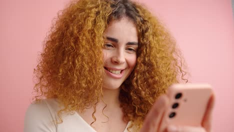 smiling female using cellphone in pink studio