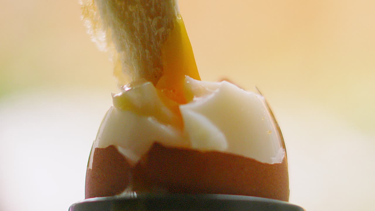 Toast Bread Being Dipped in Runny Yolk Boiled Egg with Cracked Shell for Nutritious Breakfast. Traditional Healthy Morning Food