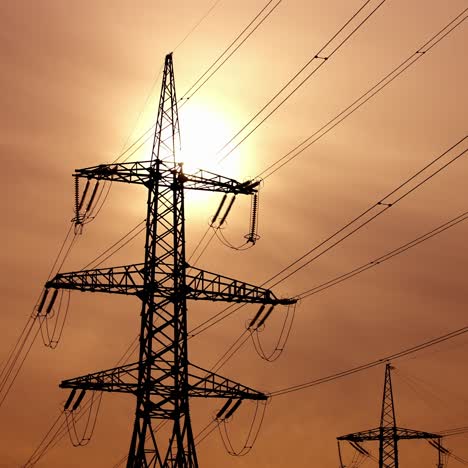 transmission lines against the evening sky. high-voltage electric towers with wires on the setting sun background. black pylons with electricity