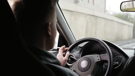 Vista-Desde-El-Asiento-Trasero:-Joven-Fumando-Cigarrillo-Mientras-Conduce-Su-Coche