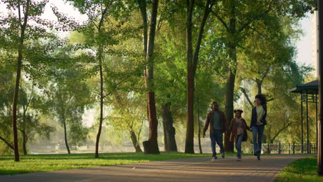 Couple-walk-holding-daughter-hands-in-empty-city-garden.-Family-leisure-time.