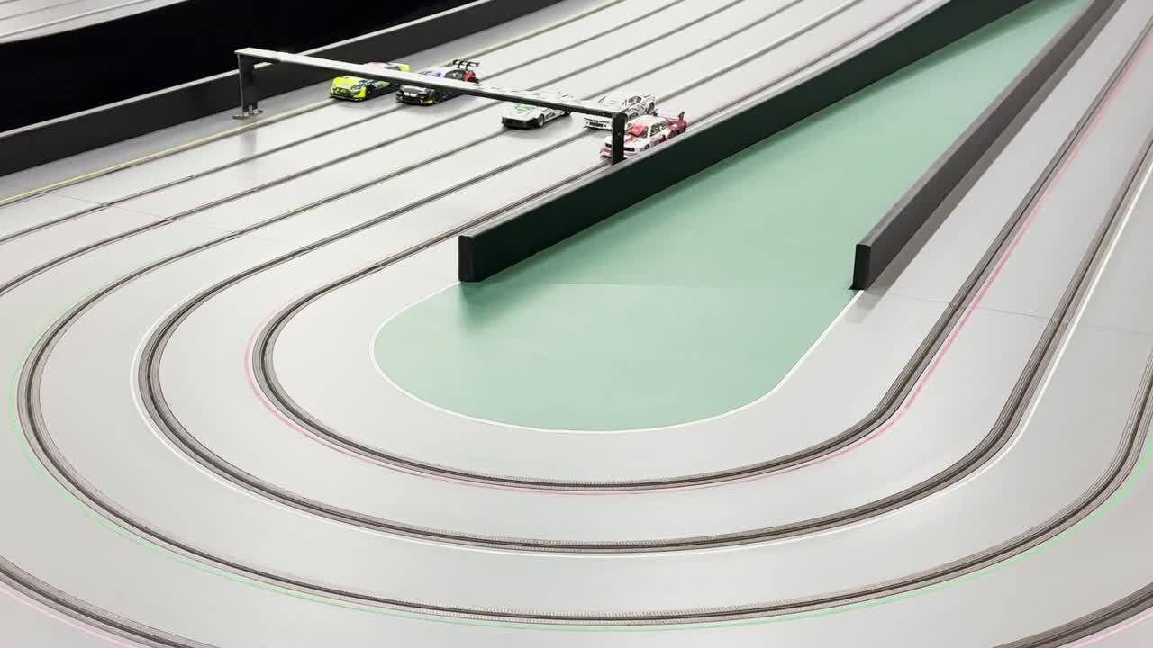 Watch as small cars speed around a smooth, curved slot track in a thrilling race.
