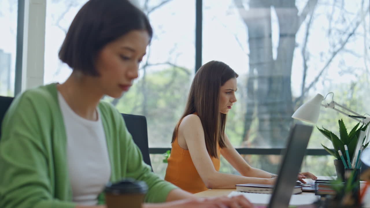 多様なグループを監督する女性チームリーダーのクローズアップ。人々はノートパソコンで忙しく作業している。
