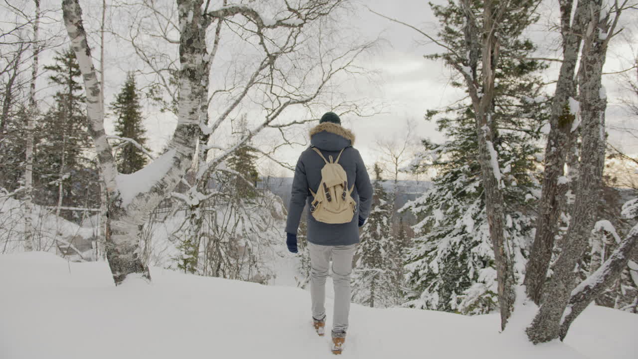 눈 덮인 숲에서 하이킹하는 남자
