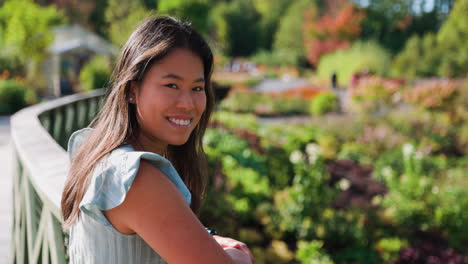 beautiful asian woman looking towards camera and smiling in beautiful vibrant park