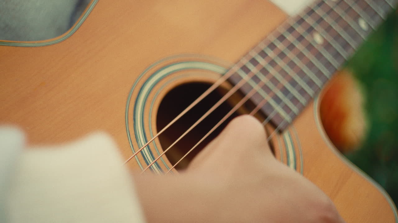 "Close-up of an acoustic guitar being played, focusing on the strings and sound hole with a soft blurred background