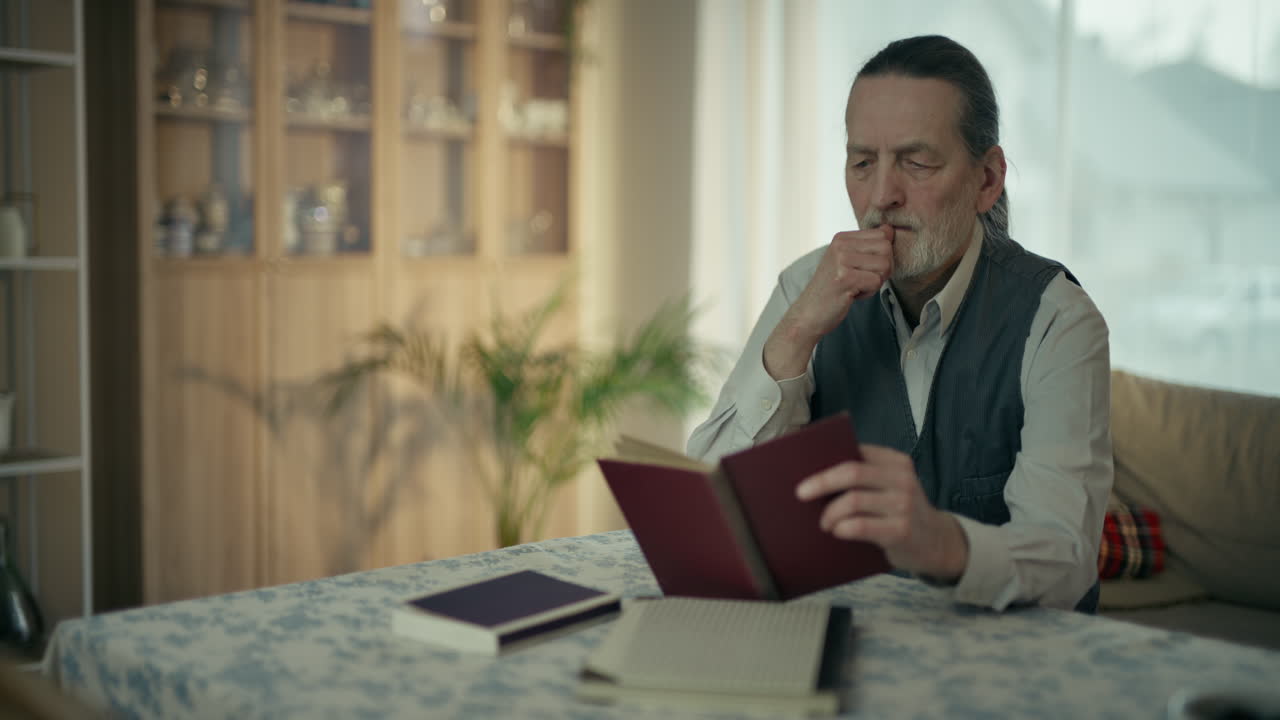 Thoughtful Senior Man Reading a Book at Home