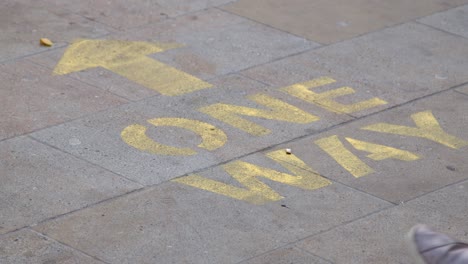 close up shot of feet walking over one way pavement marking