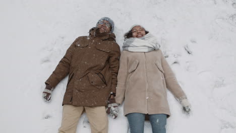 couple making snow angels in the snow