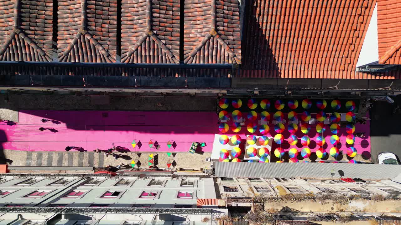 Descending over pink street with colorful umbrellas hanging.Its one of most popular places to enjoy the nightlife in Lisbon, located at Cais do Sodre,Portugal