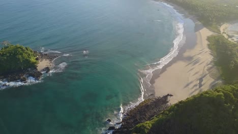 Aerial-tracking-pedestal-down-on-the-end-of-beautiful-Nacpan-Beach-near-El-Nido-at-sunset-on-Palawan,-the-Philippines