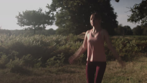 a young woman doing jumping jump in the open green covered space of the park on a sunny day