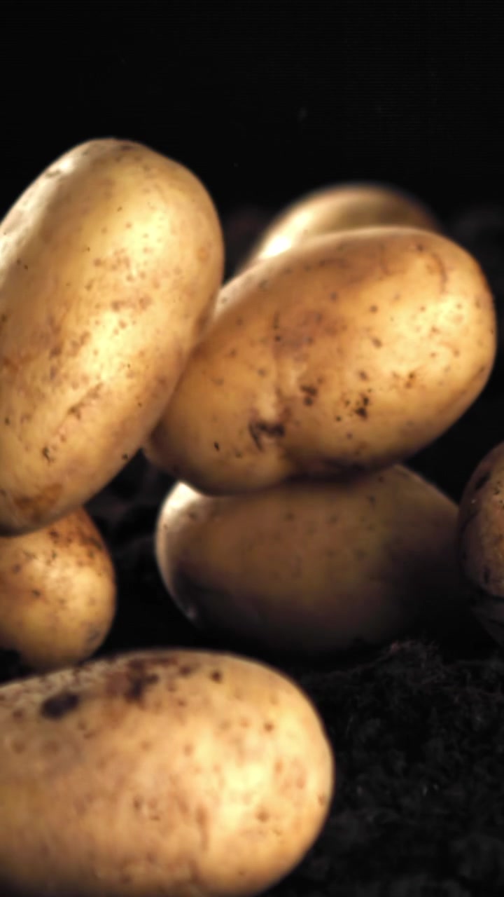 Patate al rallentatore che cadono su terreno scuro