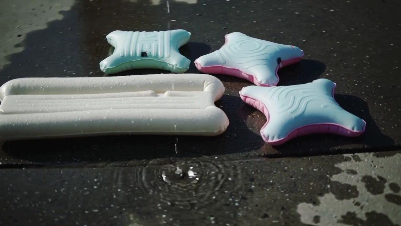 Striking droplet creating ripple on poolside tile, white lounger and star pads showing trails