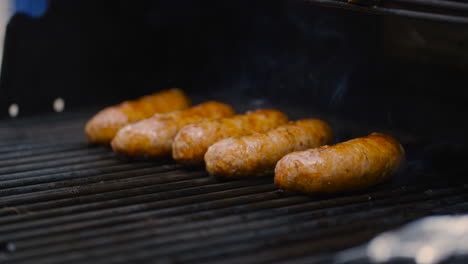fila de chisporroteantes salchichas asadas a la parrilla al aire libre