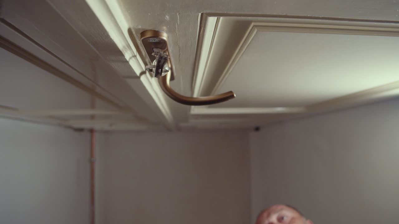 hombre cerrando la puerta de entrada con llaves, cierre de mano y ojo de cerradura, vista inferior de ángulo bajo, cara en segundo plano