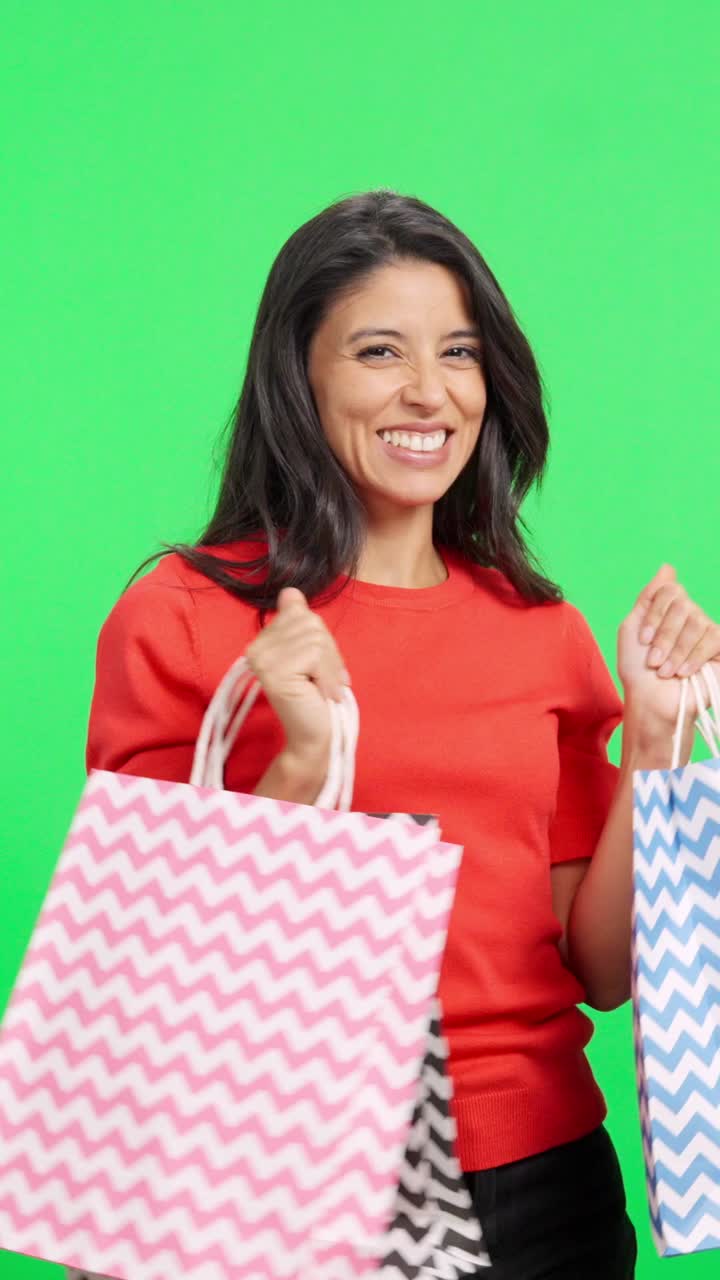 Donna entusiasta che tiene in mano colorate borse della spesa su green screen