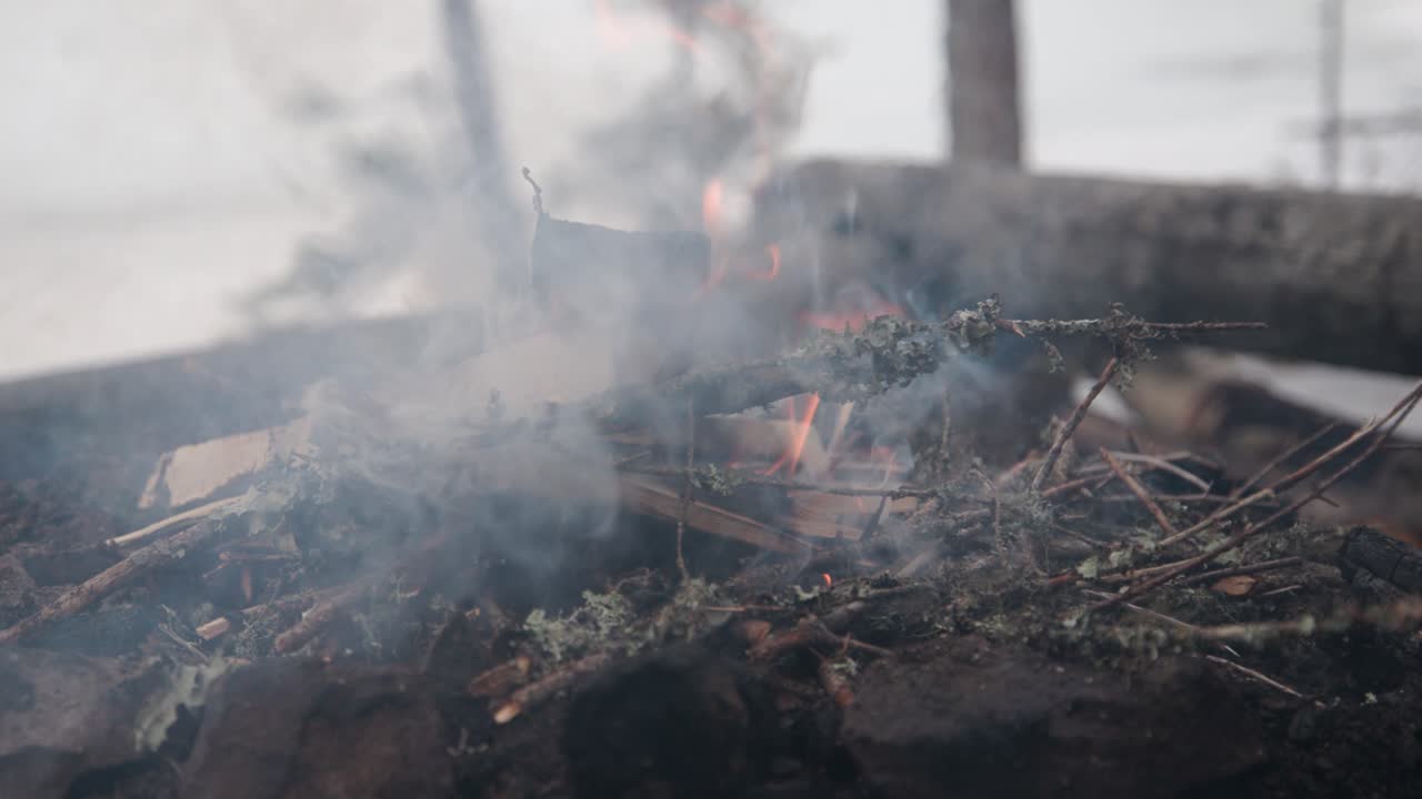 Man putting firewood on campfire, slow motion