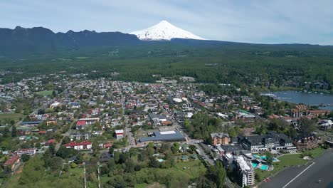 drone shot flying backward over pucon with stunning view of the town, lake and villarrica volcano in the background on a clear day