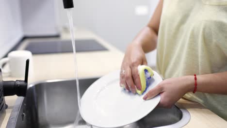 woman washing dishes and mug in kitchen sink