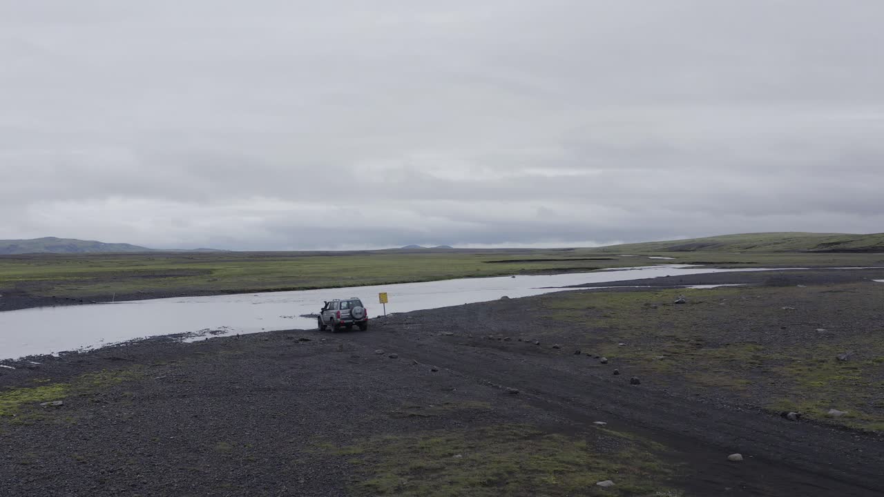 un camión todoterreno modificado vadeando hacia y cruzando el río highland durante el día
