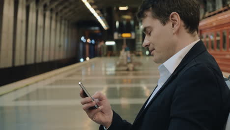 Joven-Y-Apuesto-Hombre-De-Negocios-Enviando-Mensajes-De-Texto-Al-Celular-En-El-Metro