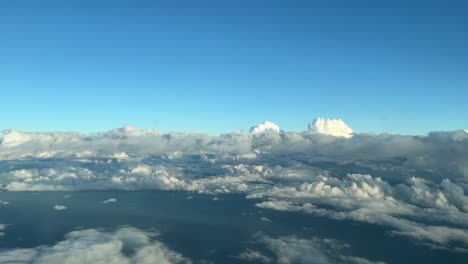 aerial view from a cockpit overflying few clouds with a deep blue sky