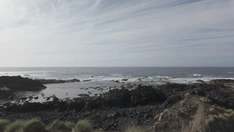 Rugged-Mosteiros,-Sao-Miguel-coastline-with-waves-breaking-against-volcanic-rocks,-sunny-day