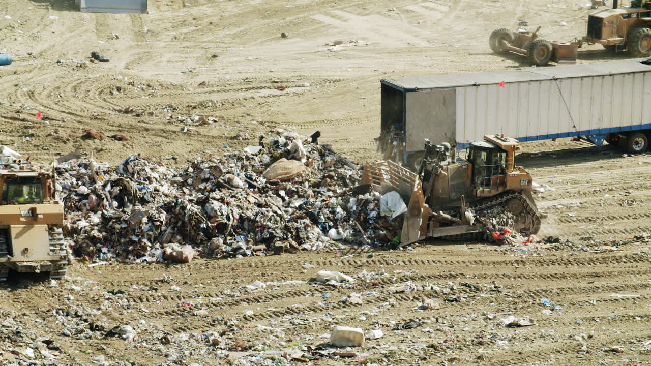 Heavy machinery and trucks at a bustling landfill site
