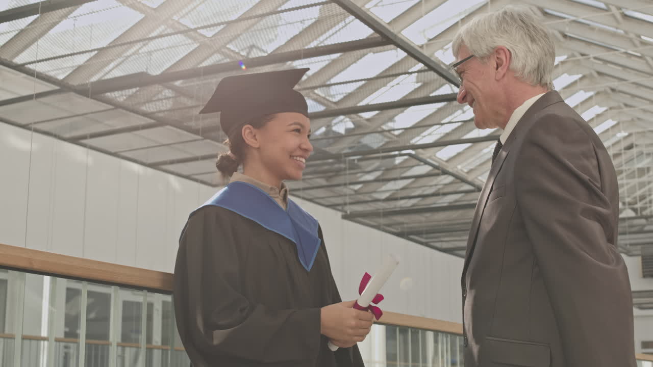 Old University Teacher Congratulating Mixed-race Female Graduate