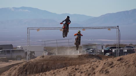 motorcycles fly over jumps and down a racetrack at during an off-road biking competition - slow motion