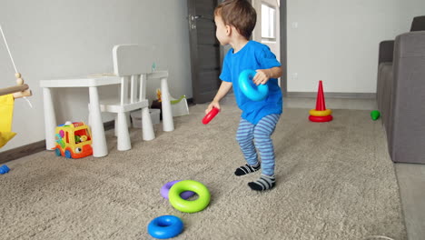 healthy caucasian child playing with toys at home. happy active toddler having a game in his room.