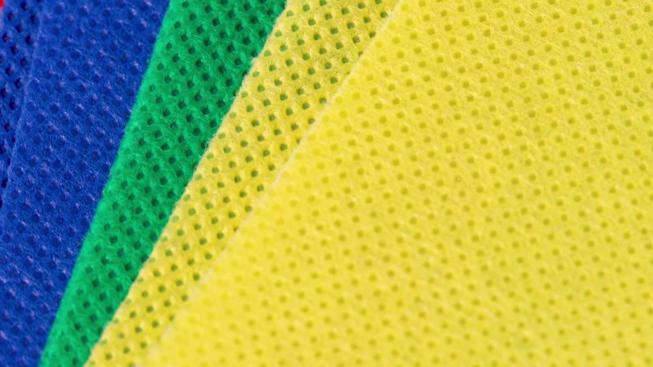 노란색, 녹색, 파란색 및 빨간색 흡수성 섬유 천 조각 매크로 샷은 회전 동작으로 보기를 닫습니다.