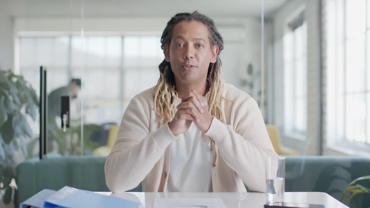 Portrait of happy biracial casual businessman talking during video call in office, slow motion