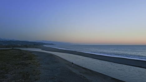 달리는 남자가 있는 해변의 저녁 전망, 차가운 파도가 있는 바다, 깊고 푸른 하늘, 멀리 있는 바투미