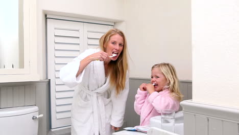 cute little girl brushing her teeth with her mother