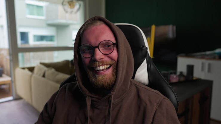 COMPUTERS - Man smiles and laughs while looking at the camera, medium shot