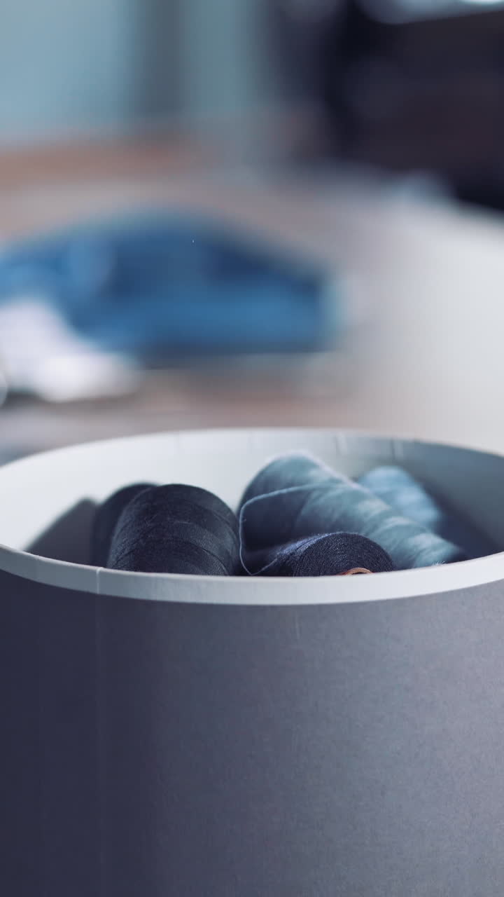 Box with thread spools. Close up view with many sewing threads against workshop Vertical video