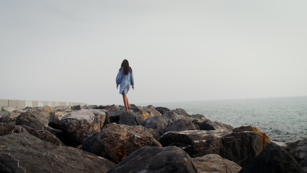 Donna che cammina sulle rocce vicino all'oceano