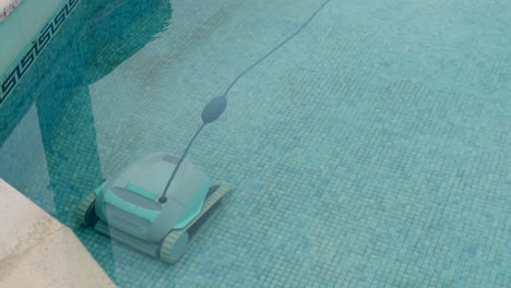 robotic pool cleaner scrubs tiled floor underwater in clear blue pool